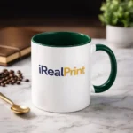 Cană personalizată cu interior verde brad și logo iRealPrint prezentată într-un decor premium cu linguriță aurie și elemente elegante, evidențiind designul sofisticat al produsuluiment relaxant de cafea