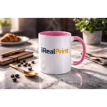 Cană personalizată cu interior roz pastel și logo iRealPrint prezentată într-un decor premium cu linguriță aurie și elemente elegante, evidențiind designul sofisticat al produsului