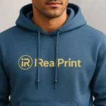 Prim-plan hanorac bărbați personalizat indigo evidențiind logo iRealPrint, gluga, șireturile și finisajul premium al materialului