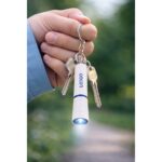 Breloc cu lanternă LED albastru personalizat atașat la chei, context outdoor cu utilizare reală și branding discret profesional