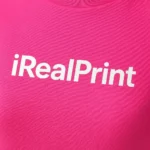Detaliu logo iRealPrint aplicat prin transfer termic alb pe tricou damă personalizat purpuriu, evidențiind claritatea personalizării