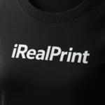 Detaliu personalizare logo iRealPrint aplicat prin transfer termic alb pe tricou damă personalizat negru, evidențiind textura materialului