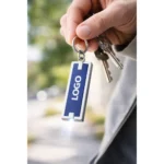 Breloc cu lumină LED albastru folosit pe chei în context real, mini lanternă promoțională practică pentru activități zilnice și branding vizibil